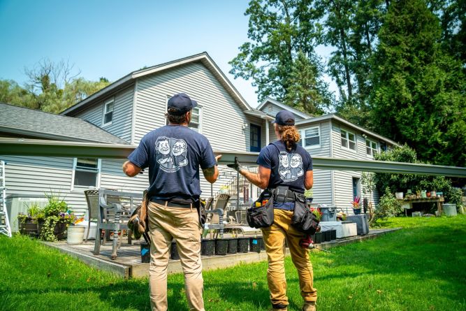 Brothers carrying a gutter up to a house for home repair