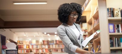 6 must-read books before buying into a franchise. Woman in book store looking to purcahse best franchise books.