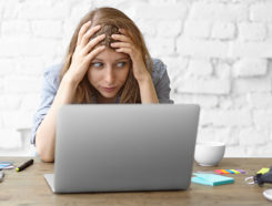 Woman sitting in front of computer with hands on her head in frustration