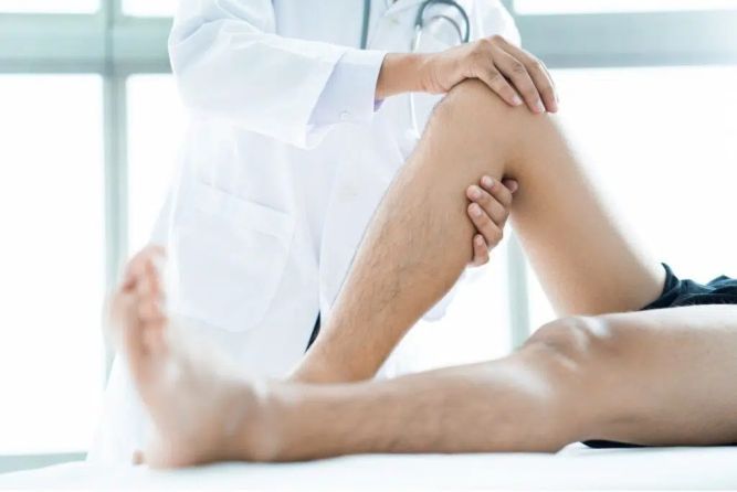 QC Kinetix Franchise Doctor giving knee exam
