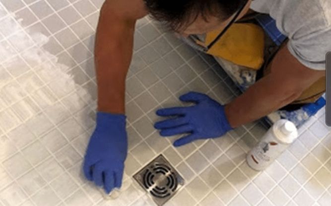Sir Grout franchise worker installing grout into shower tile.